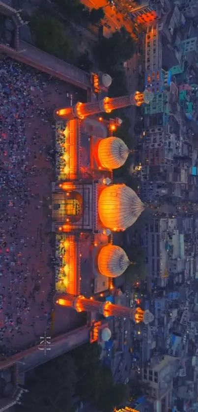 Aerial view of an illuminated mosque at night with vibrant cityscape.