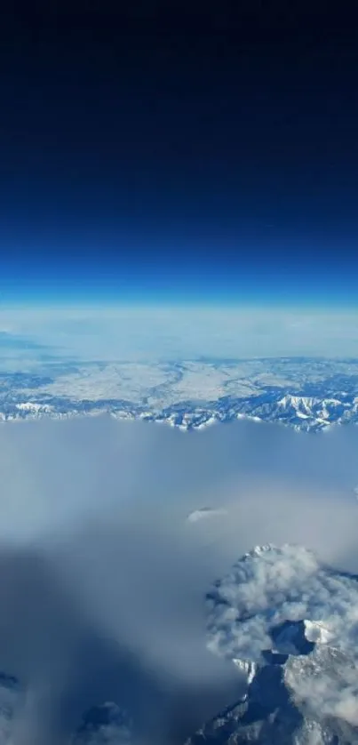 Aerial view of snow-capped mountains under a vast blue sky, offering a serene landscape.