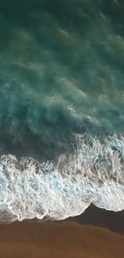 Aerial view of teal ocean waves crashing gently on a sandy beach.