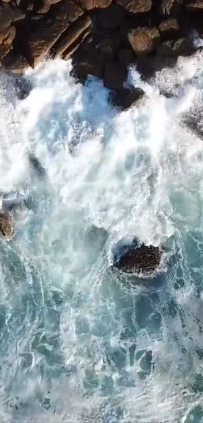 Aerial view of ocean waves crashing against rocky shore, featuring vibrant blue water.