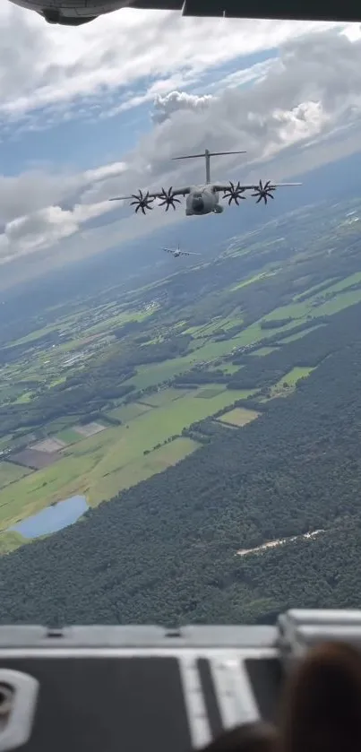 Military aircraft over vibrant green landscape from aerial view.