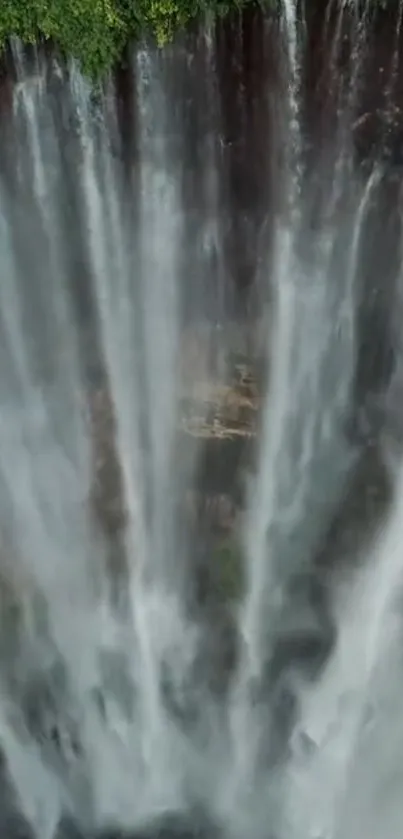 Aerial view of a stunning waterfall with lush green foliage on a mobile wallpaper.