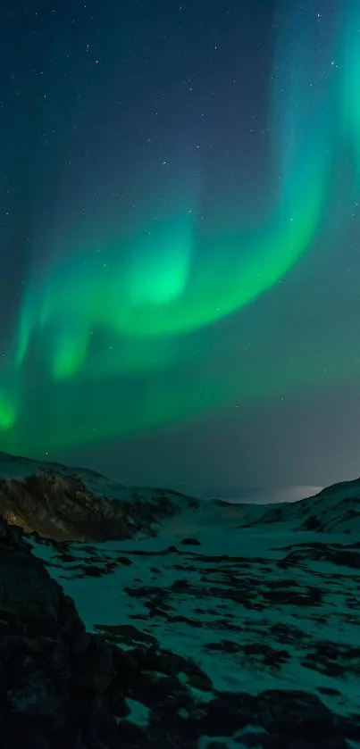 Aurora Borealis over snowy mountains with vibrant green lights in the night sky.