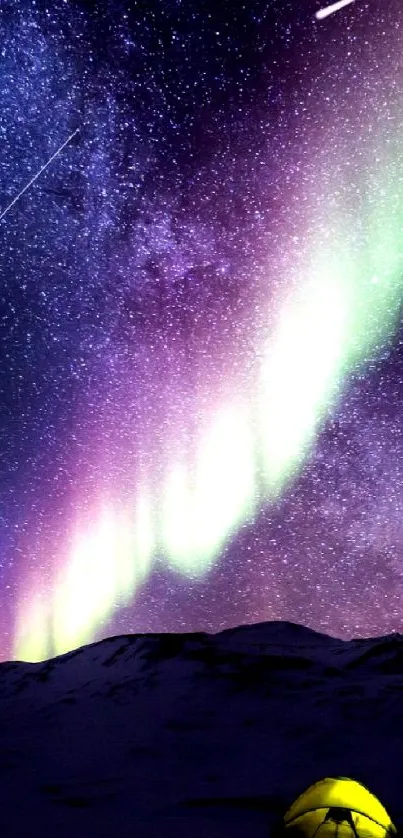 Aurora Borealis glowing over mountains and tent with starry night sky.