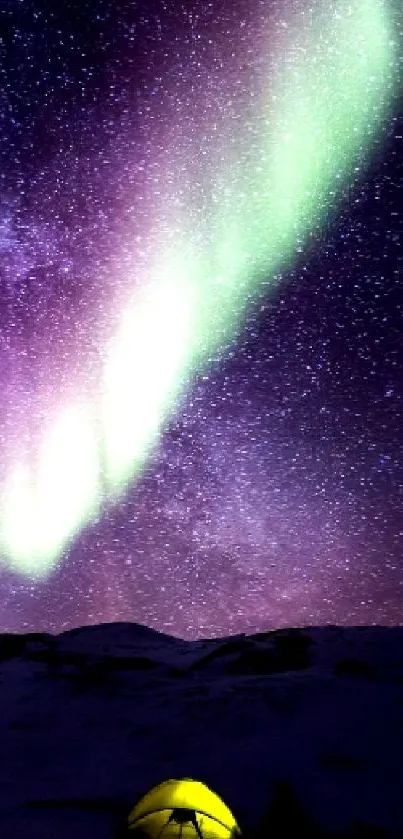 Aurora borealis illuminating a starry night above a tent in the mountain landscape.