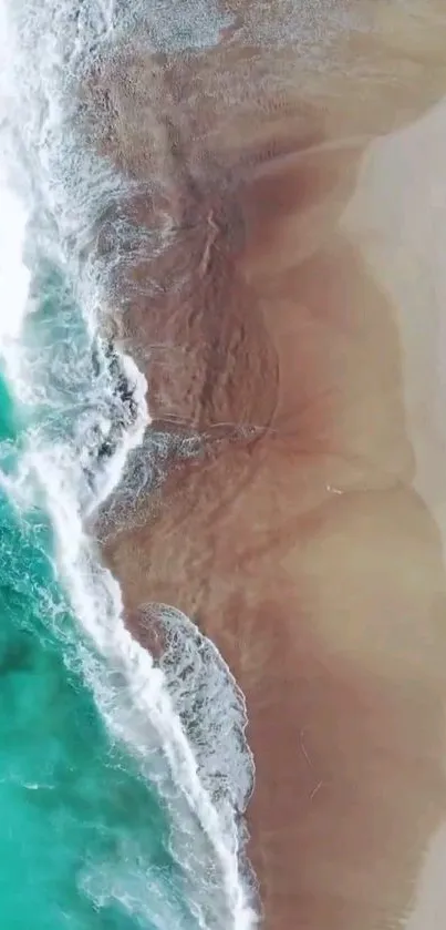 Aerial view of turquoise ocean waves hitting sandy beach.