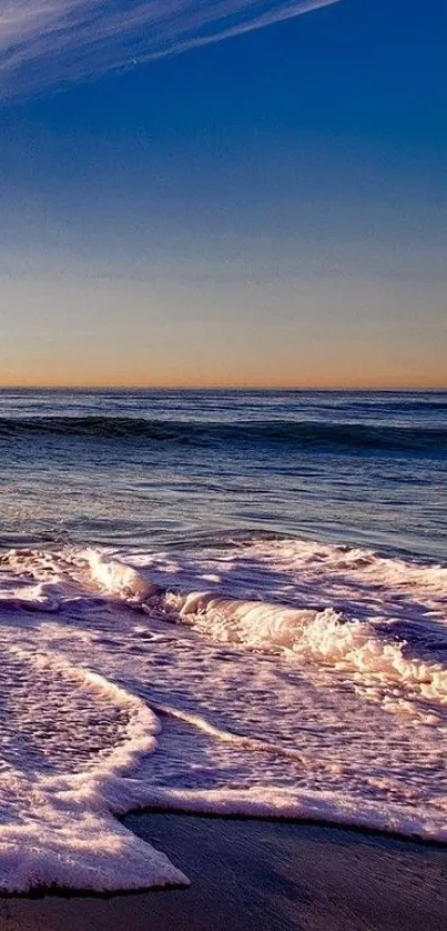 Peaceful beach sunset with ocean waves against a vibrant sky.