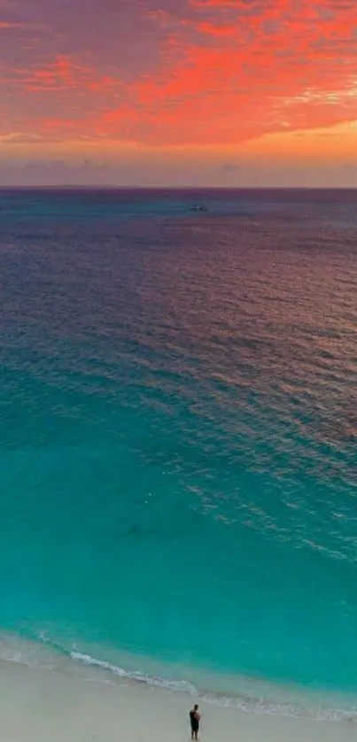 Turquoise beach with vibrant orange sunset sky.