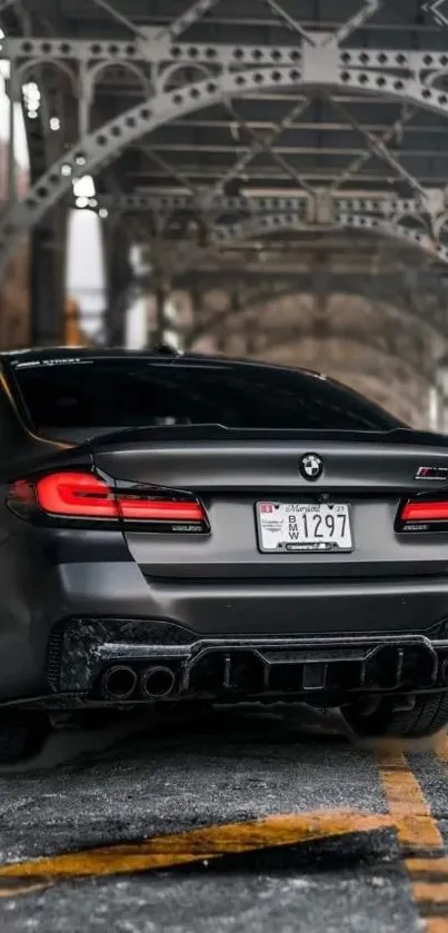 Sleek BMW car under an urban bridge, perfect for mobile wallpaper.