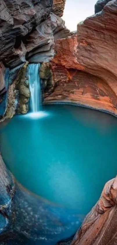 Canyon waterfall with blue pool and red rock formations, creating a serene scene.