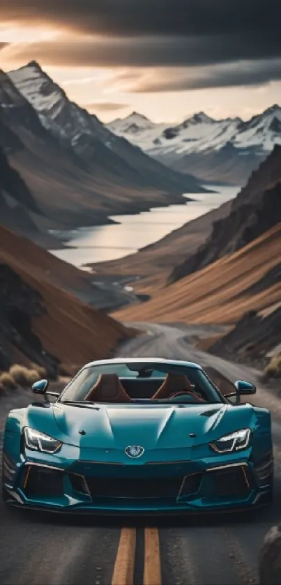 Blue sports car on mountain road with snowy peaks and lake during sunset.