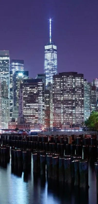 Illuminated city skyline at night with reflections on water.