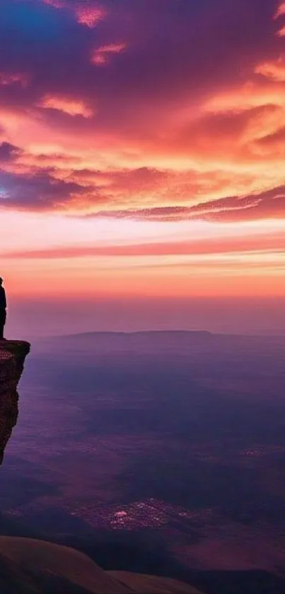 Silhouette on cliff at sunset with vibrant sky and clouds