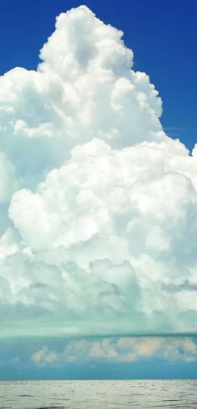 White clouds tower over a calm sea under a clear blue sky.