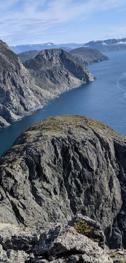 Panoramic view of a coastal cliff meeting the ocean under a bright sky.