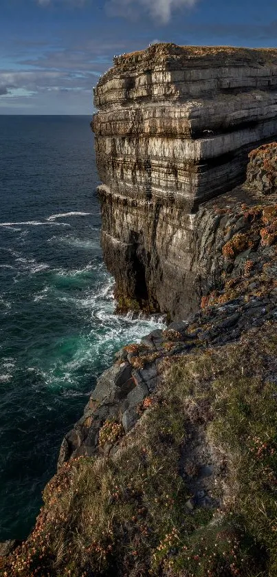 Rugged cliff beside calm ocean under a clear blue sky.