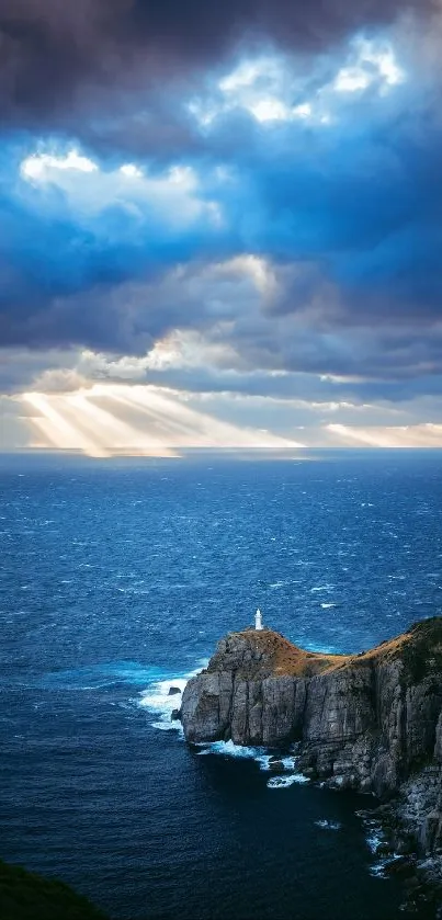 Lighthouse on rocky cliff under dramatic sunset sky at sea.