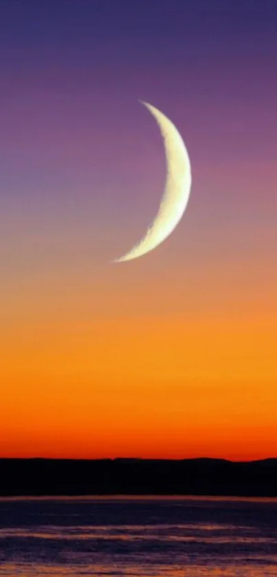 Crescent moon over vibrant orange sunset sky with ocean view.