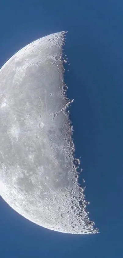 Crescent moon with detailed surface against a dark blue sky.