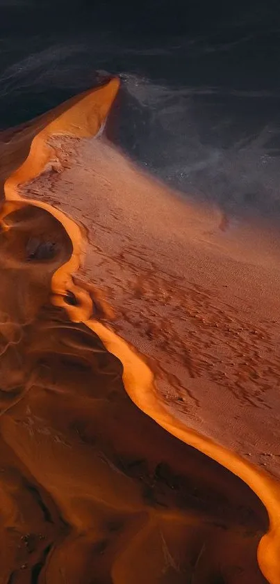 A stunning aerial view of orange sand dunes under a dark sky.