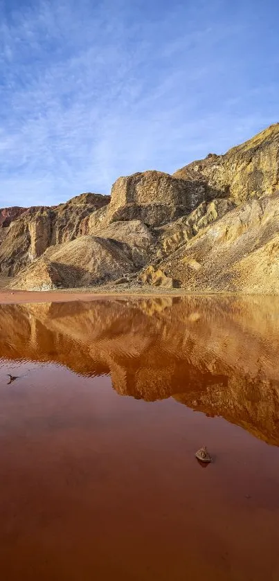 Desert mountain reflecting in calm water under a vivid blue sky.