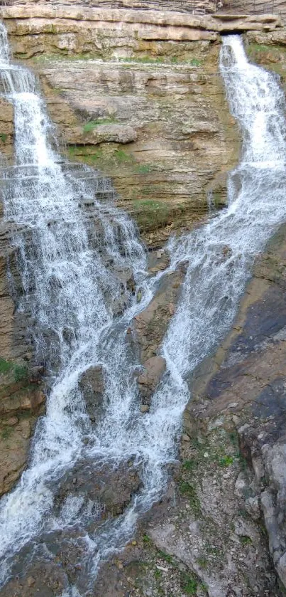 Double waterfall cascading over rocky cliffs with surrounding greenery.