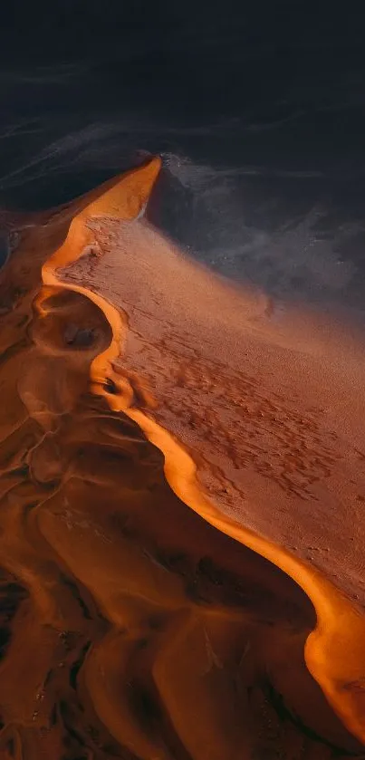 Stunning aerial view of a sunlit dune with rich dark orange colors.
