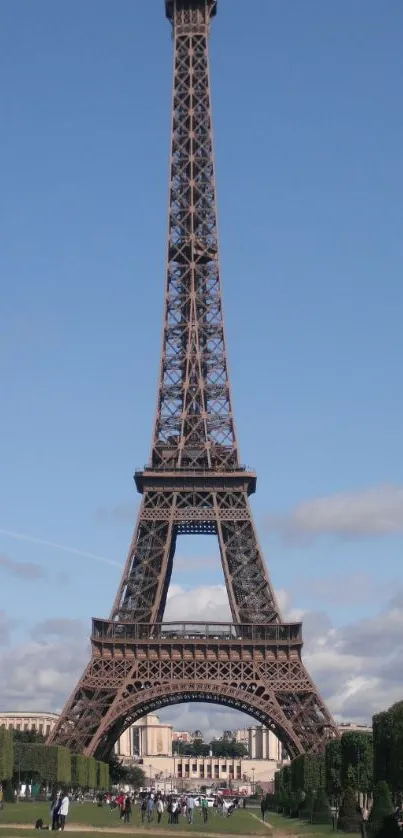 Eiffel Tower against a clear blue sky with greenery in the foreground.