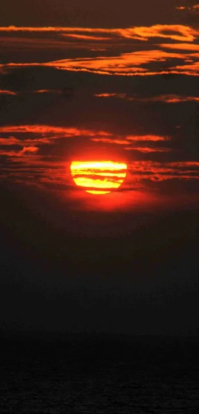 Fiery sunset with red and orange glow against dark clouds in a bold scenic view.