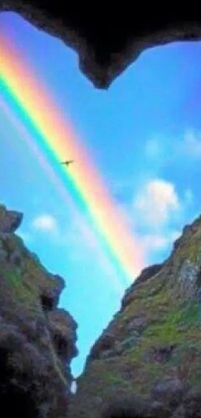 Heart-shaped rock framing a vivid rainbow in the sky.