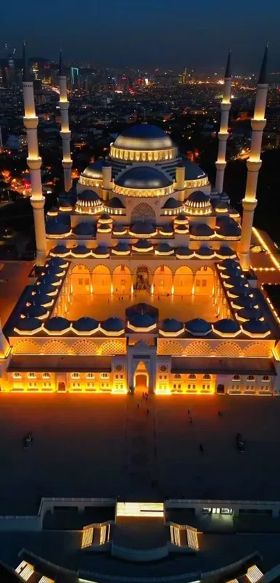 Aerial view of a beautifully illuminated mosque against a night cityscape backdrop.