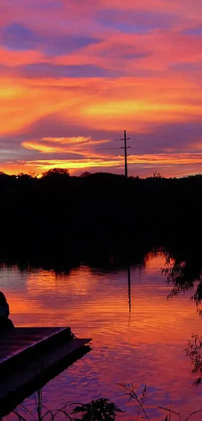 Lakeside sunset with vivid orange and purple sky reflecting on calm water.