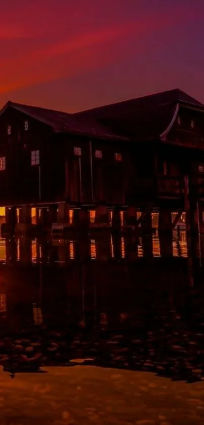 Lakeside cabin at sunset with vivid sky reflection.