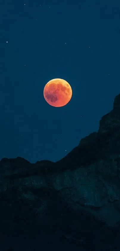 Lunar eclipse over dark mountain silhouette at night.