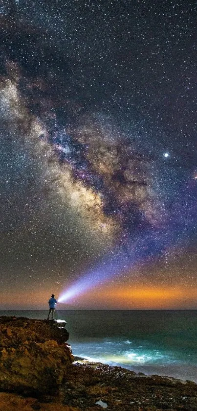 Person stands on cliff gazing at the Milky Way in a star-filled night sky.