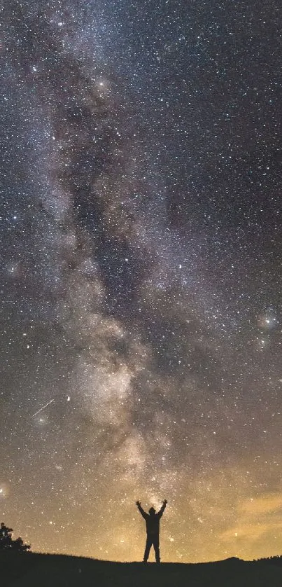 Silhouette under starry Milky Way sky with vibrant cosmic colors.