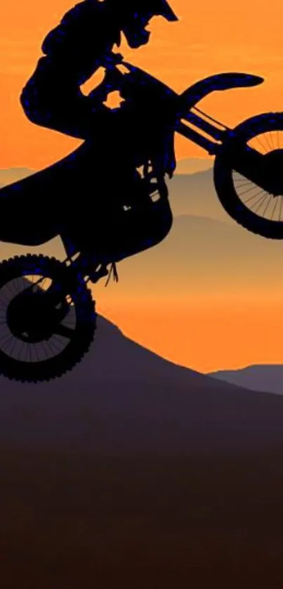 Motocross biker silhouette against a vibrant orange sunset over hills.