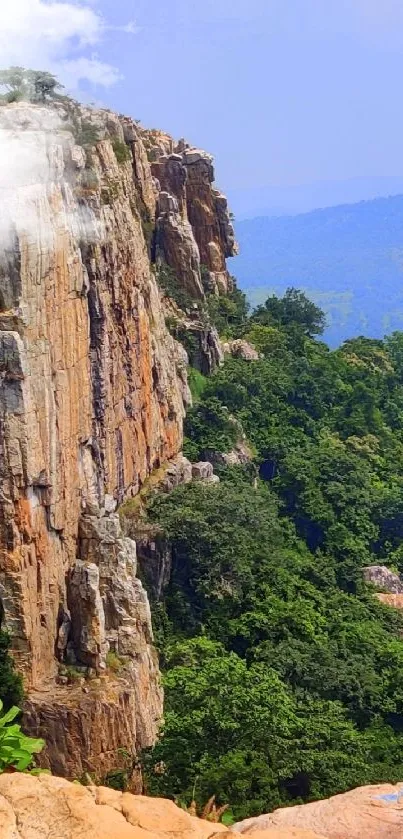 Rugged mountain cliff with lush green valley in the background.