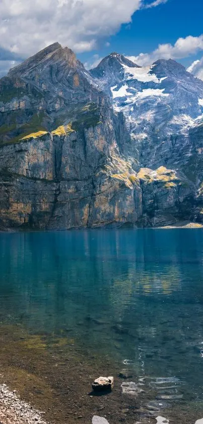 Mountain lake with clear water and towering peaks under a blue sky.