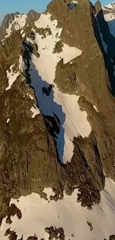 Majestic mountain peaks with snow patches under clear blue skies.