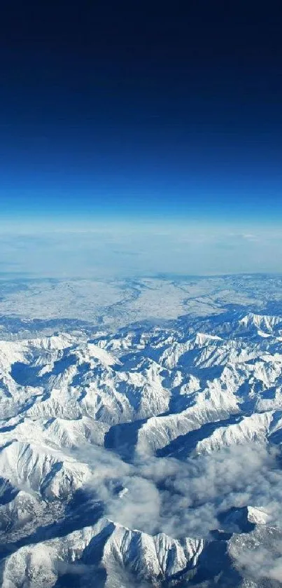 Aerial view of snow-covered mountains with a deep blue sky.