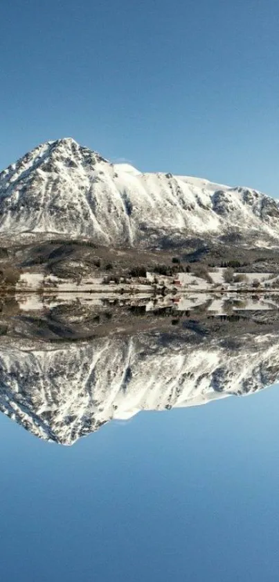 Snowy mountain perfectly reflected in a calm lake under a clear blue sky.