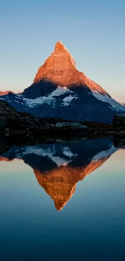 Mountain reflecting in calm water at sunrise.