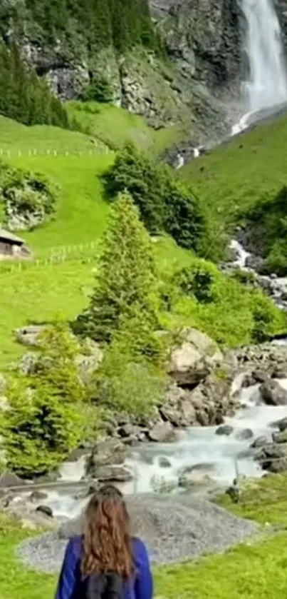 Mountain waterfall with lush green landscape and clear blue sky.