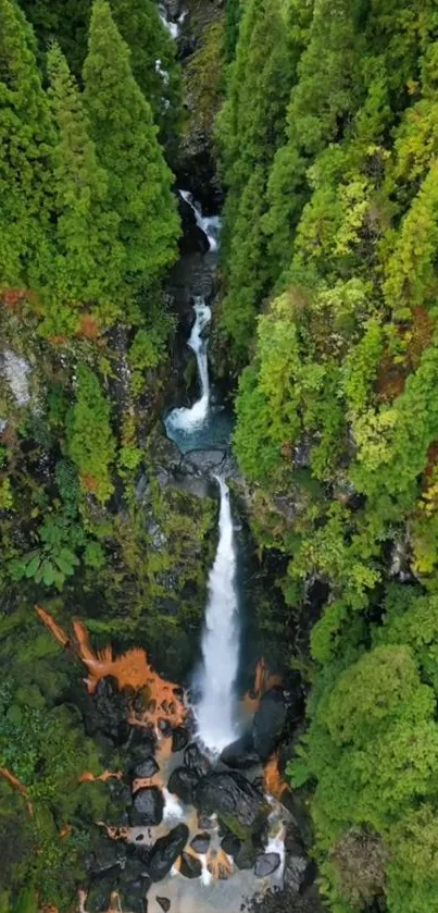 Aerial view of a stunning waterfall surrounded by lush green forest.