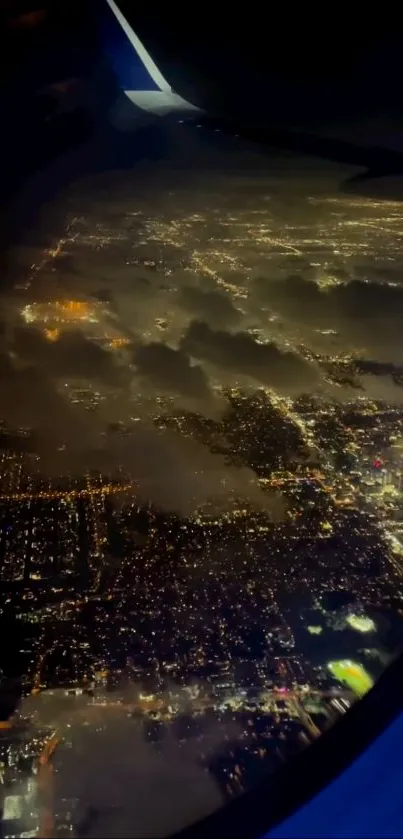 Aerial night view of a glowing cityscape seen from a plane window.