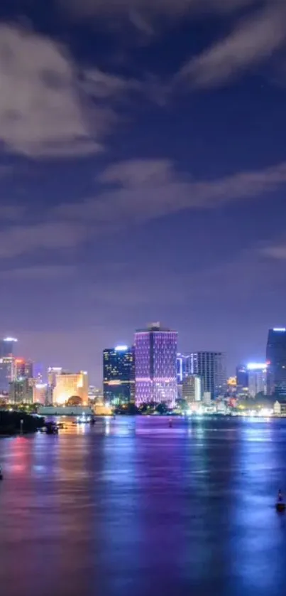 Night cityscape with buildings and river reflections in vibrant colors.