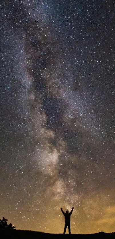 Night sky with Milky Way and silhouetted figure raising arms.