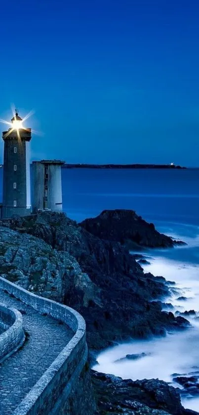 Lighthouse glowing at night overlooking a vast deep blue ocean.