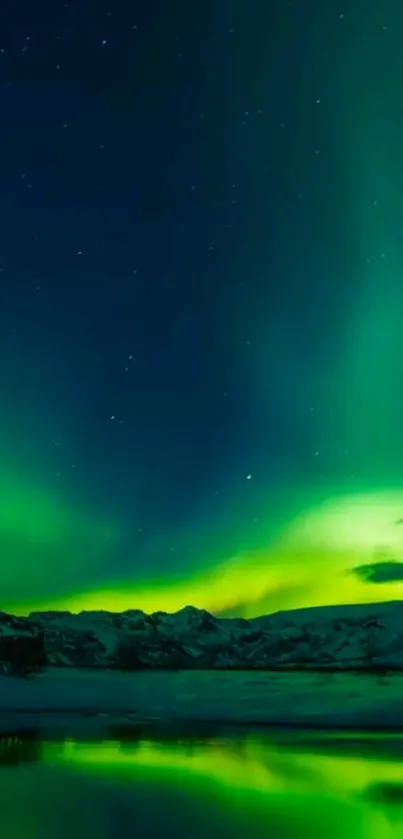 Vibrant green aurora borealis over snowy mountains and reflective lake.